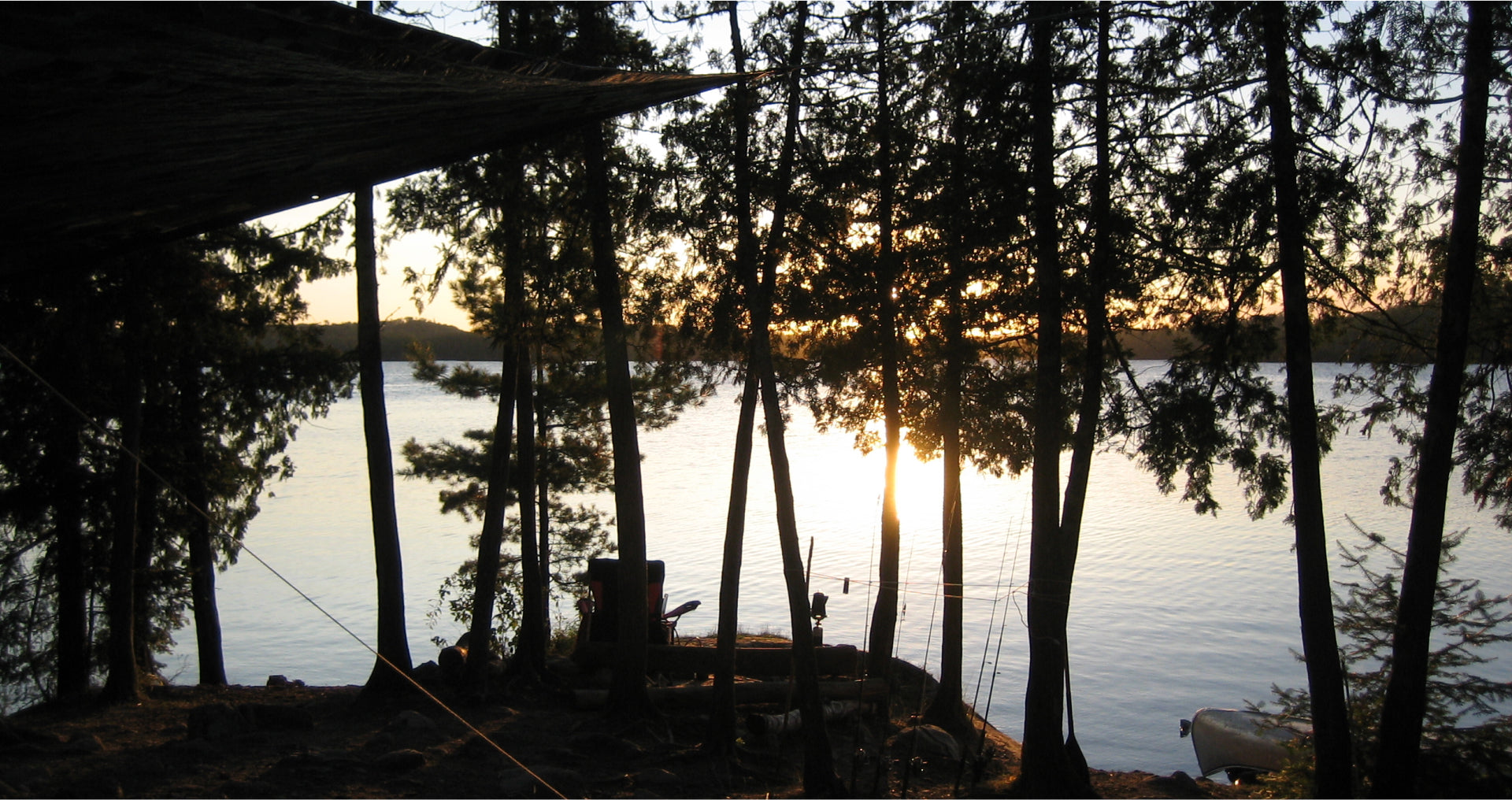 Sunset view of a campsite in the Boundary Waters, with trees silhouetted against a calm lake. The campsite belongs to Max Winders and his family.