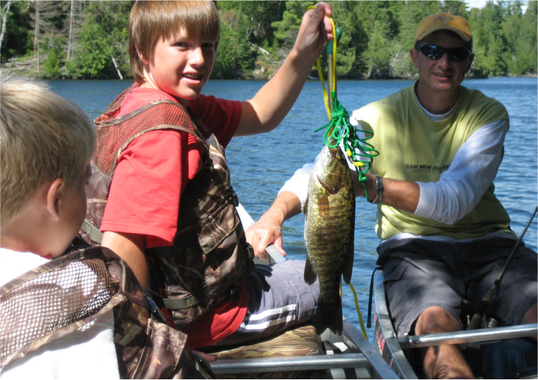 Max Winders and his son Jeremy holding a large fish they caught during a fishing trip in the Boundary Waters, with another son, Jack, looking on in excitement.